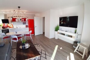 A modern kitchen with a dining area, a flat-screen TV mounted on the wall, and a red refrigerator. - Holiday apartment in Glowe with swimming pool (Glowe)