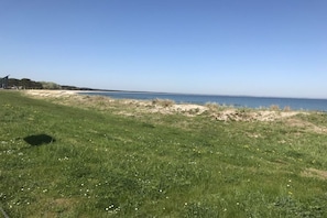 A grassy area with a clear view of the sea and a distant shoreline.