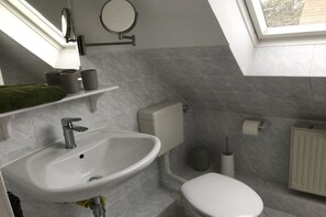 A bathroom with a white sink, toilet, and a window.