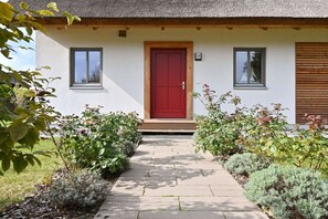 Ein Haus mit einer roter Tür, der Aufschrift '13' darüber und einem Weg zum Eingang.