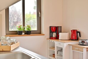 Eine Küche mit Fenster, einer Kaffeemaschine, einem Toaster und einem Wasserkocher.