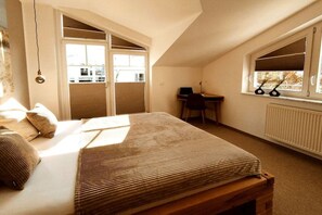 Un dormitorio con cama, escritorio y ventana con persianas.