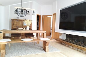 A dining area with a wooden table, chairs, and a large flat-screen TV. - Holiday apartment with 2 bedrooms (Juliusruh)