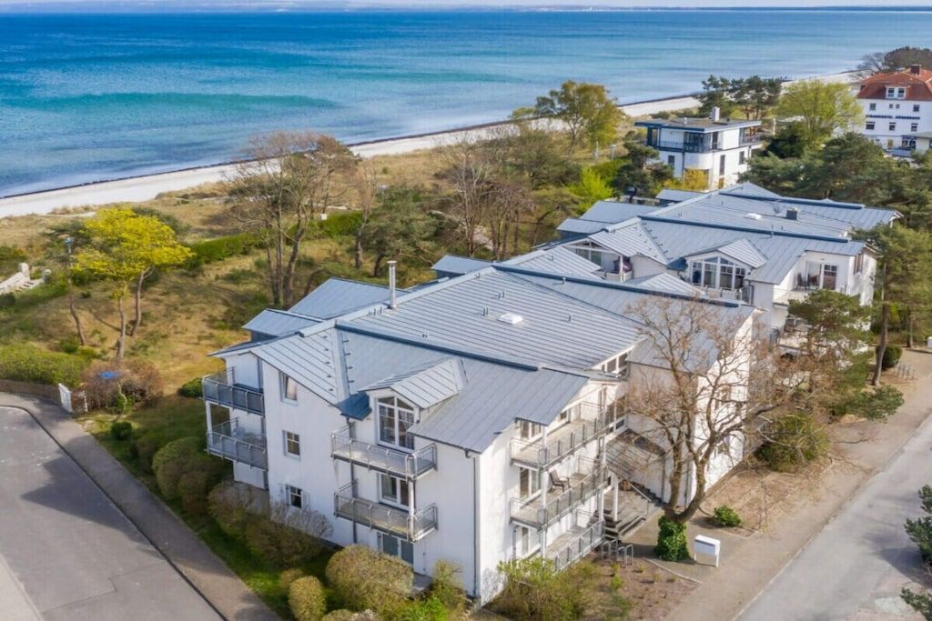 A coastal residential area with modern houses, a beach, and a clear view of the sea.