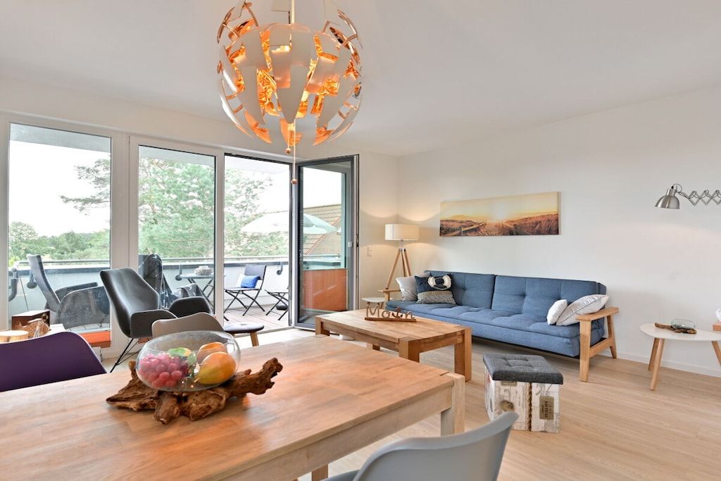 Un salon moderne avec un canapé bleu, une table basse en bois et un lustre original.
