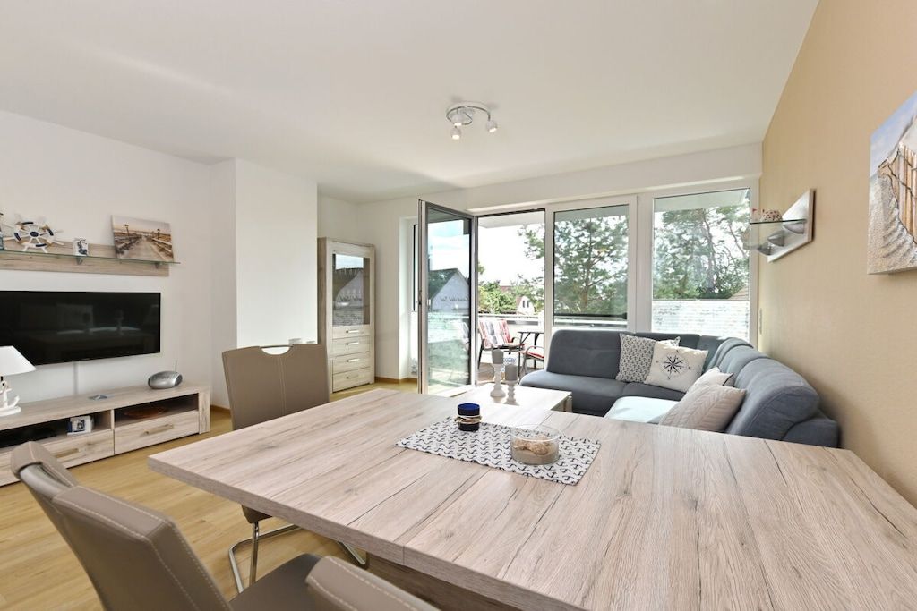 A modern living room with a flat-screen TV, a dining table, and a sofa.