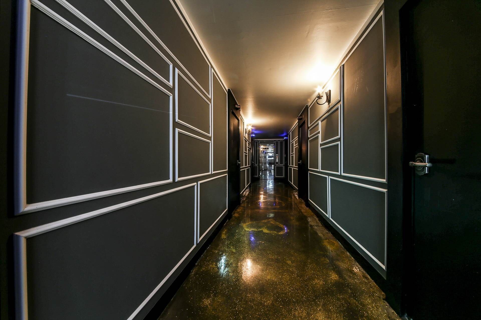 A hallway with a shiny, reflective floor leading to a door at the end.