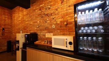 Un área de kitchenette equipada con refrigerador, microondas y cafetera.