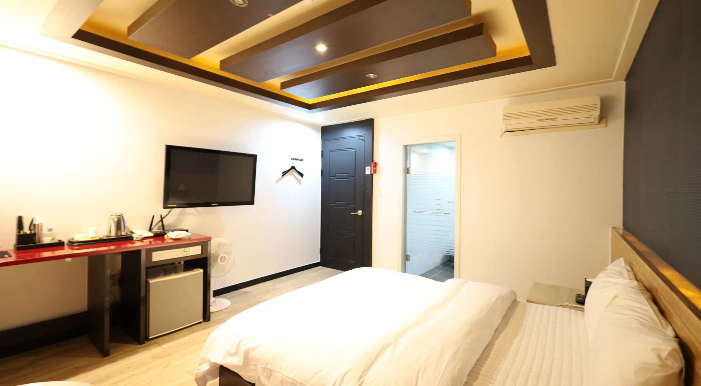 Una habitación de hotel con cama, escritorio con televisor, armario y puerta.