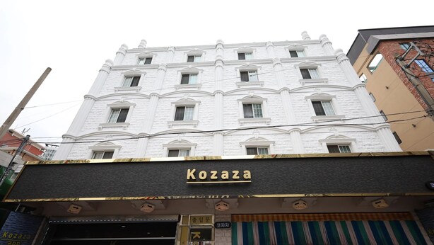 Un edificio con fachada blanca y un letrero que dice 'Kozaza'.