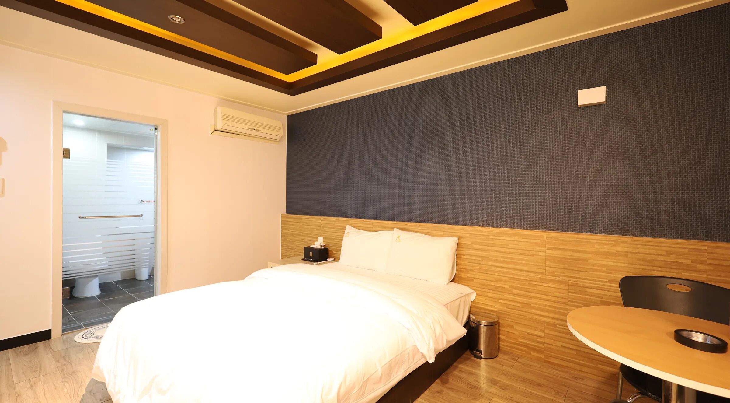 Una habitación de hotel con cama, mesita de noche y una pequeña mesa redonda.