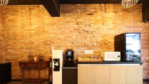 Una cocina con pared de ladrillo, un refrigerador, un microondas, una cafetera y una encimera de madera.