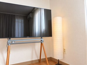 A flat-screen TV on a stand with a lamp beside it.