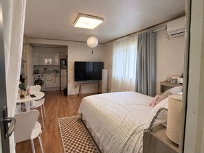 Habitación de hotel compacta con cama, televisión, kitchenette pequeño y baño.