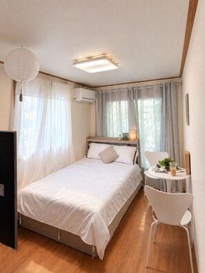 Un dormitorio moderno con cama, mesita de noche y una pequeña mesa redonda con silla.