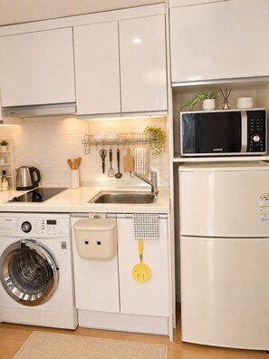Una cocina funcional equipada con lavadora, microondas y pileta.