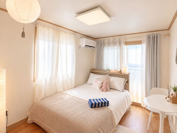 A bedroom with a bed, a bedside table, a chair, and a window with curtains.