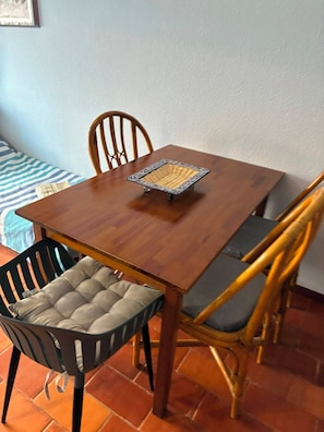 A dining table with a woven placemat, surrounded by chairs with cushioned seats. - Pé na Areia House, Armação de Pêra (Armação de Pêra)