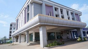 A modern building with a covered entrance, large windows, and a flat roof. - Deluxe Hotel Utkarsh (Silvassa)