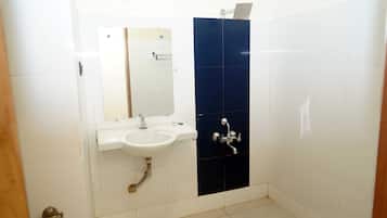 Een badkamer met een wit wastafelmeubel, een spiegel en een douche met een donkerblauwe wand.