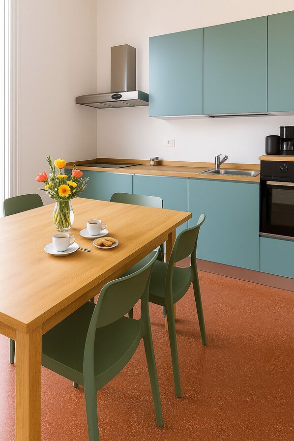 Una cocina moderna con gabinetes azul verdosos, una mesa de madera y un florero con flores.