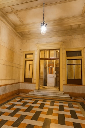 A room with a checkered floor, a chandelier, and a door with a window. - Residenze dell'Alloro - Gorizia House (Palermo)