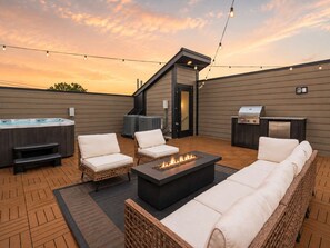 A rooftop patio with outdoor seating, a hot tub, a grill, and string lights. - Stunning Nash retreat w/ hot tub and rooftop view! (Nashville)