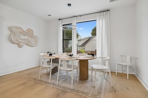 A dining area with a round table, white chairs, and a view of the outside. - Stunning Nash retreat w/ hot tub and rooftop view! (Nashville)