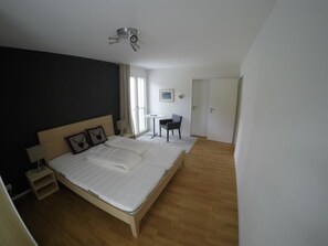 A bedroom with a large bed, bedside tables, a chair, a small table, and a door. - Mühlehof D4 Appartement/Fewo, Dusche oder Bad, WC 4 1/2-Zimmerwohnung by Interhome (Davos)