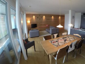 A modern living room with a dining area, wooden flooring, and a large window. - Mühlehof D4 Appartement/Fewo, Dusche oder Bad, WC 4 1/2-Zimmerwohnung by Interhome (Davos)