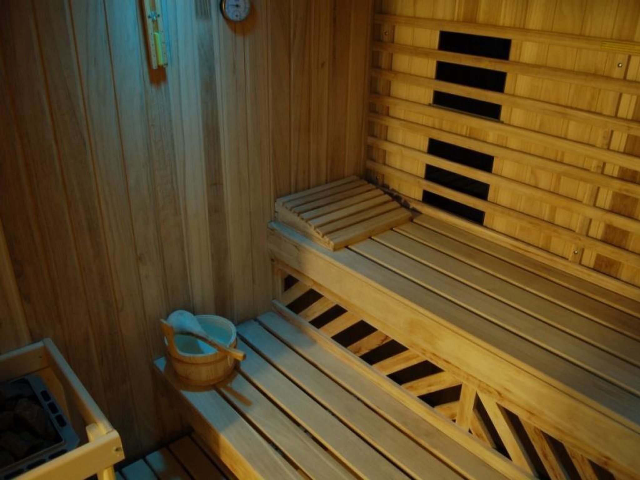 Eine Holzsauna mit Bänken und einem Holzeimer.