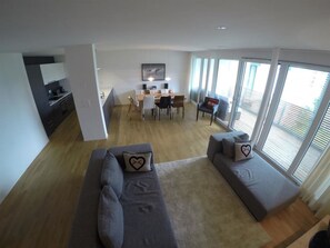 A modern living room with a sofa set, a dining area, and large windows. - Mühlehof D4 Appartement/Fewo, Dusche oder Bad, WC 4 1/2-Zimmerwohnung by Interhome (Davos)