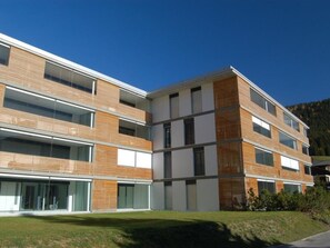 A multi-story building with a modern architectural design, featuring a combination of brick and glass facades, and a flat roof. - Mühlehof D4 Appartement/Fewo, Dusche oder Bad, WC 4 1/2-Zimmerwohnung by Interhome (Davos)