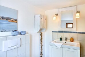 A bathroom with a white sink, a mirror, and a framed picture above the mirror. - Vrbo Property (Hasselberg OT Bobeck)