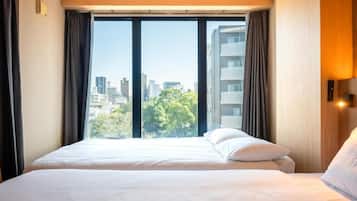 A hotel room with a large bed, a window with curtains, and a view of the cityscape.