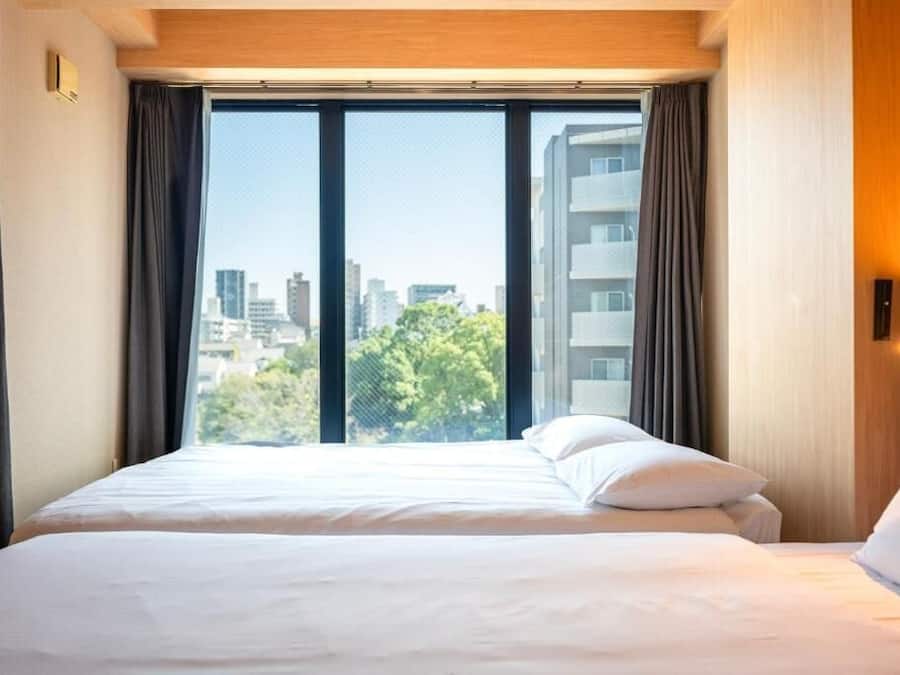 Ein Hotelzimmer mit einem großen Bett, einem Fenster mit Vorhängen und Blick auf die Stadt.