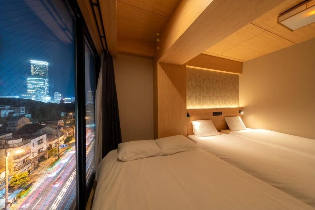 Habitación de hotel con un ventanal grande, una cama y una lámpara de pared.