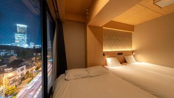 Habitación de hotel con un ventanal grande, una cama y una lámpara de pared.
