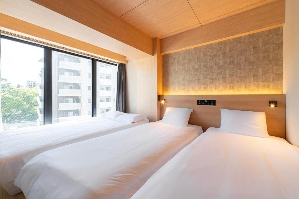Een hotelkamer met twee bedden, grote ramen en een modern design.
