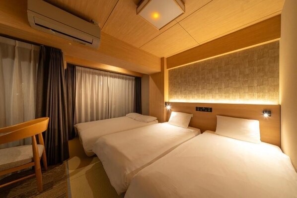Habitación de hotel con dos camas, un escritorio y un aire acondicionado.