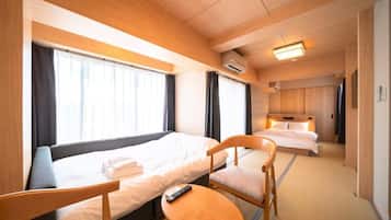 A hotel room with two beds, a small table, and a chair.