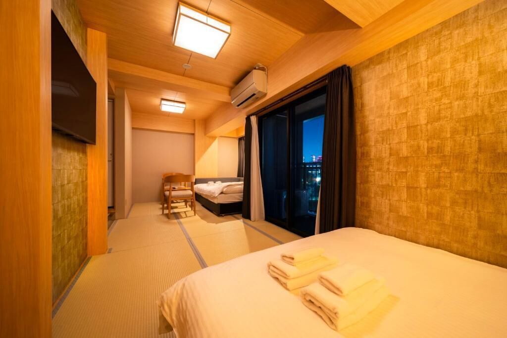 A hotel room with a bed, a desk, a chair, and a large window with curtains.