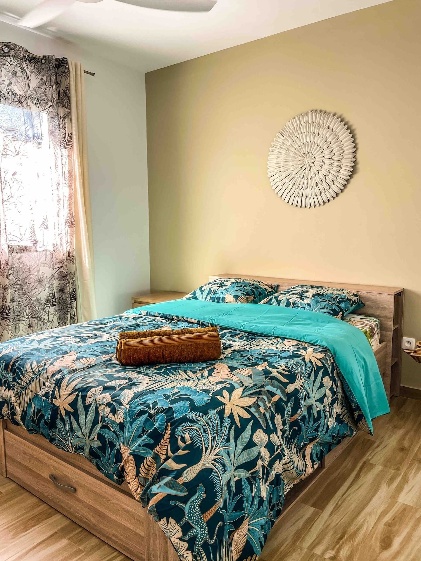 Un dormitorio con cama, cabecera de madera, decoración en la pared y ventana con cortinas.