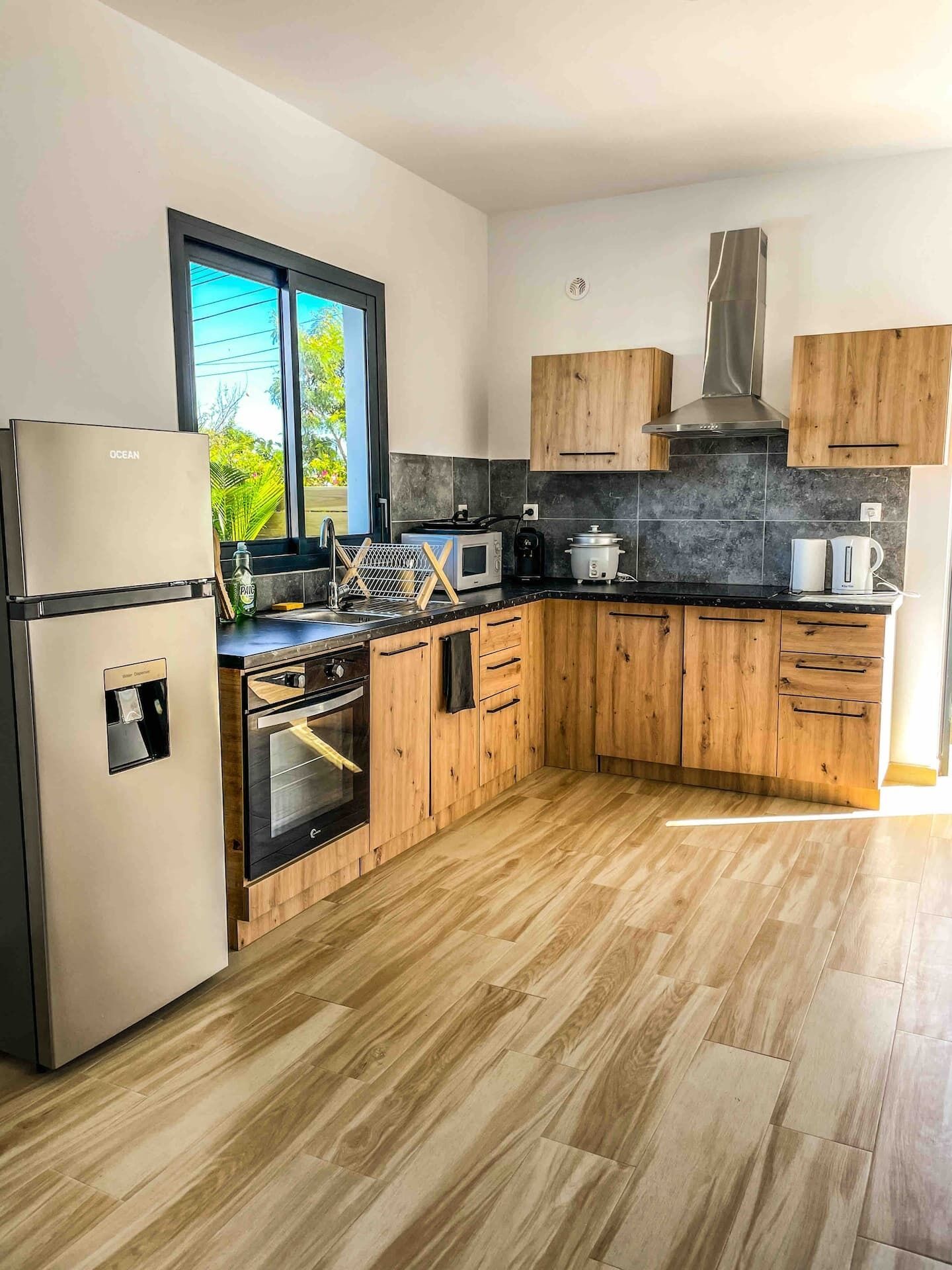 Una cocina moderna con armarios de madera, un refrigerador de acero inoxidable, un microondas y una estufa.