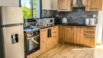 Una cocina moderna con armarios de madera, un refrigerador de acero inoxidable, un microondas y una estufa.