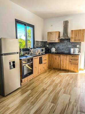 Una cocina moderna con armarios de madera, un refrigerador de acero inoxidable, un microondas y una estufa.