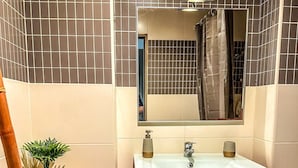 Un bagno con un mobile lavabo rosso, uno specchio e una piccola pianta in vaso.