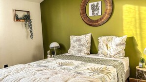 Una camera da letto con un letto, una decorazione circolare a parete, un piccolo tavolo con una lampada e una pianta sospesa.