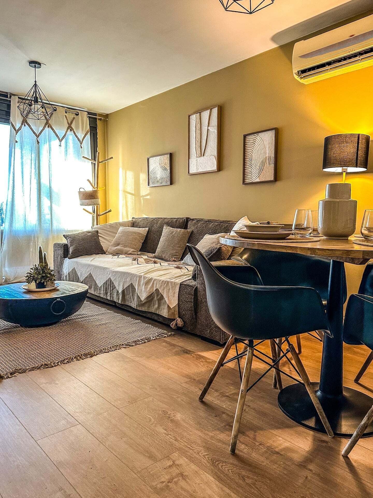 Una sala de estar moderna con un sofá, una mesa de comedor con sillas y obras de arte en las paredes.