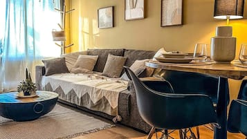 Una sala de estar moderna con un sofá, una mesa de comedor con sillas y obras de arte en las paredes.